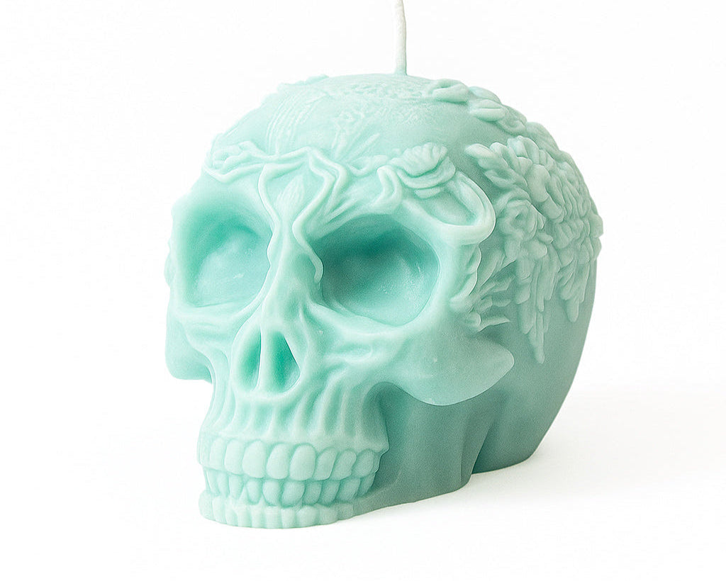 Mint green skull-shaped candle on a white background